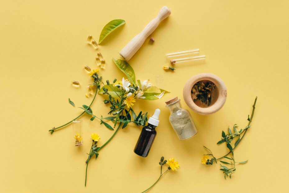 erbe aromatiche con mortaio in legno, boccetta in vetro e contagocce su sfondo giallo